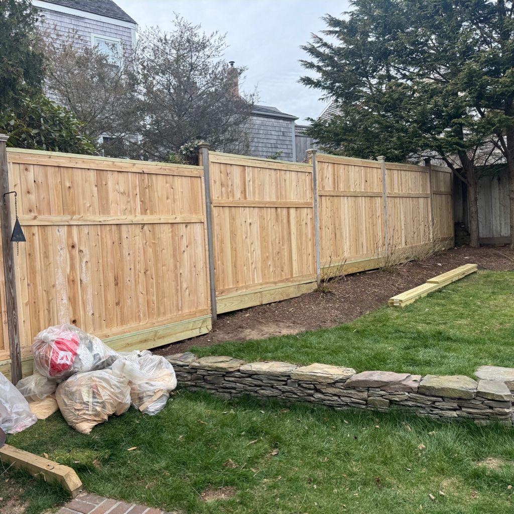 New cedar privacy fence beside a stone retaining wall