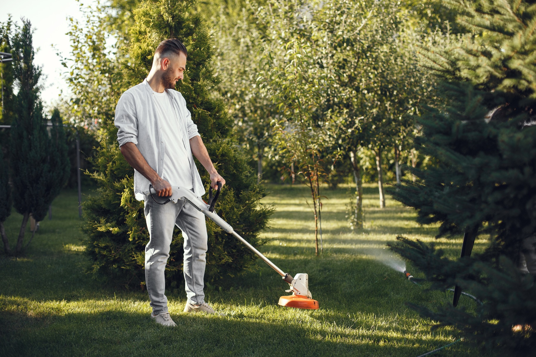 Landscape professional string trimming a garden